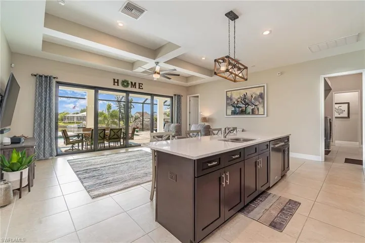Kitchen featuring a kitchen island with sink, sink, hanging light fixtures, and stainless steel dishwasher