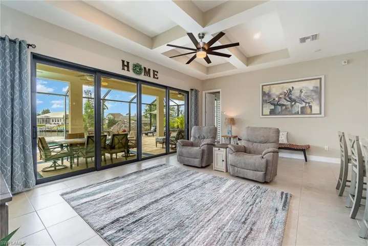 Tiled living room with beam ceiling, a wealth of natural light, ceiling fan, and coffered ceiling