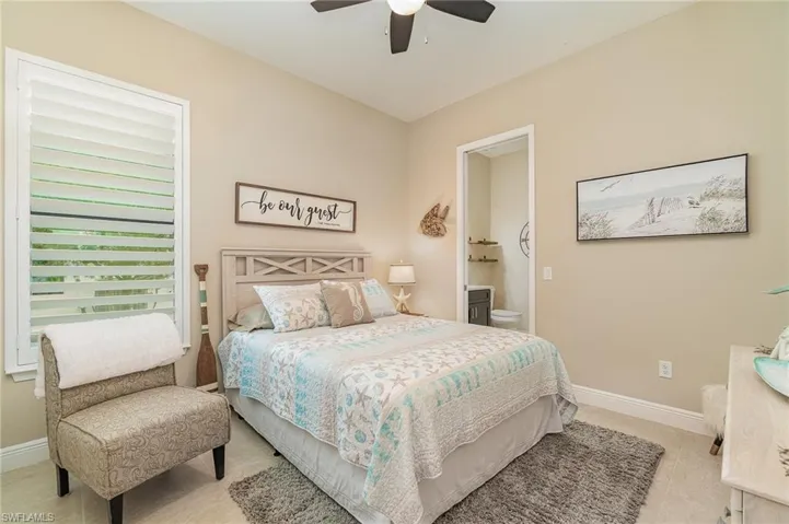 Tiled bedroom featuring ensuite bathroom and ceiling fan