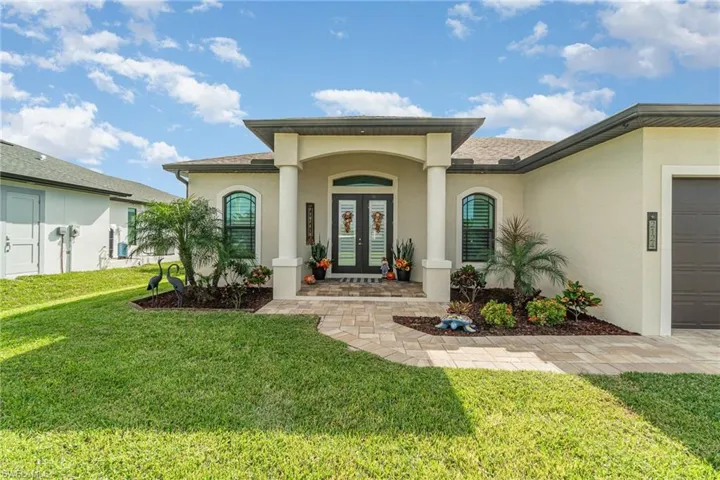 View of exterior entry featuring a yard, french doors, and a garage