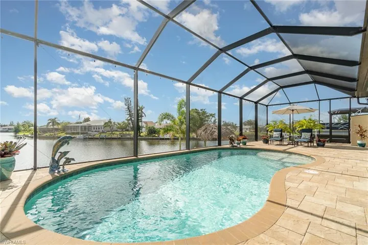 View of swimming pool with glass enclosure, a water view, and a patio