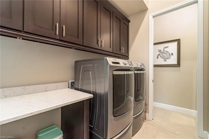 Clothes washing area featuring light tile patterned flooring, cabinets, and separate washer and dryer