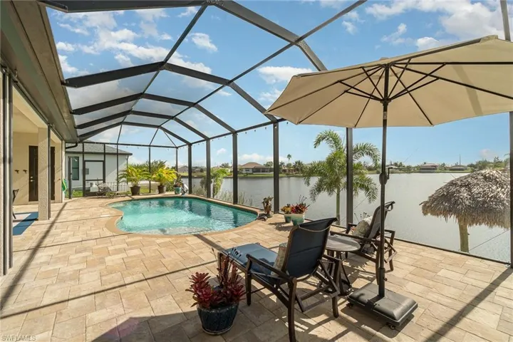 View of pool featuring a patio, a water view, and glass enclosure