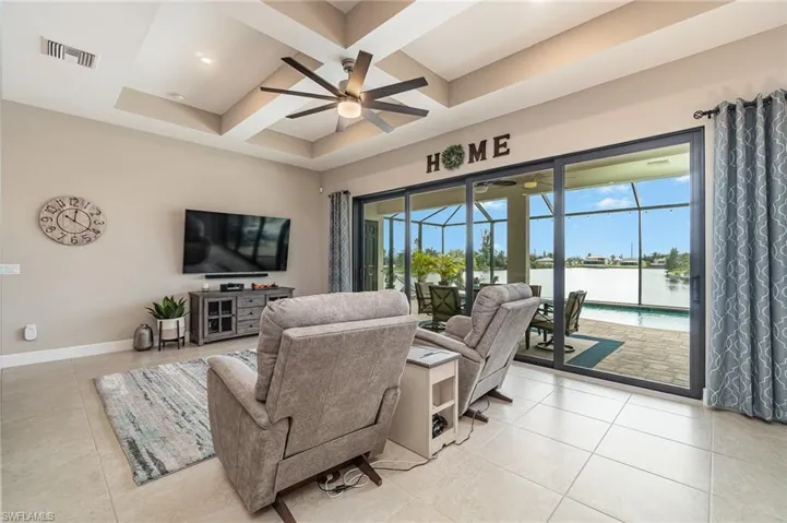 Tiled living room with beamed ceiling, ceiling fan, and coffered ceiling