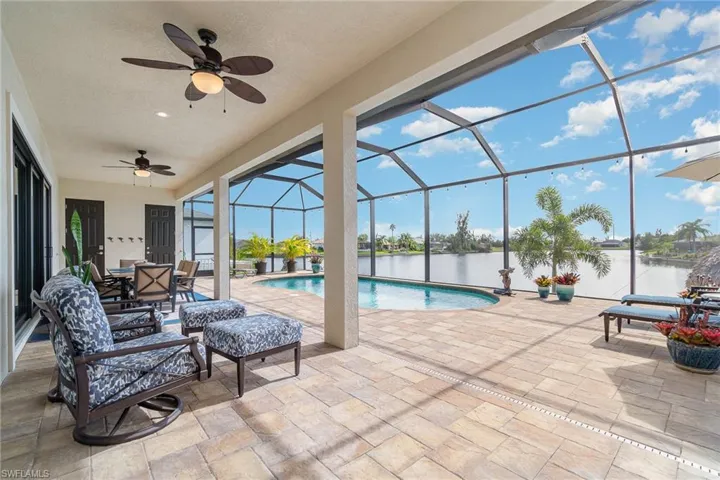 View of swimming pool with ceiling fan, a water view, a patio, and lanai enclosure