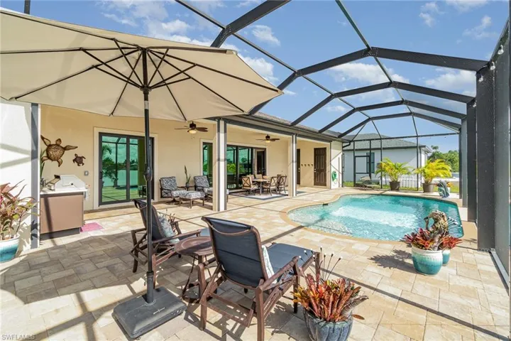 View of pool with glass enclosure, ceiling fan, and a patio