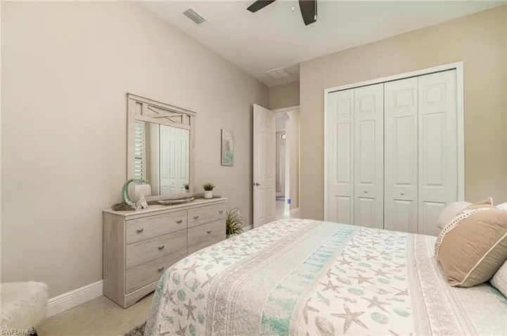 Tiled bedroom featuring ceiling fan and a closet