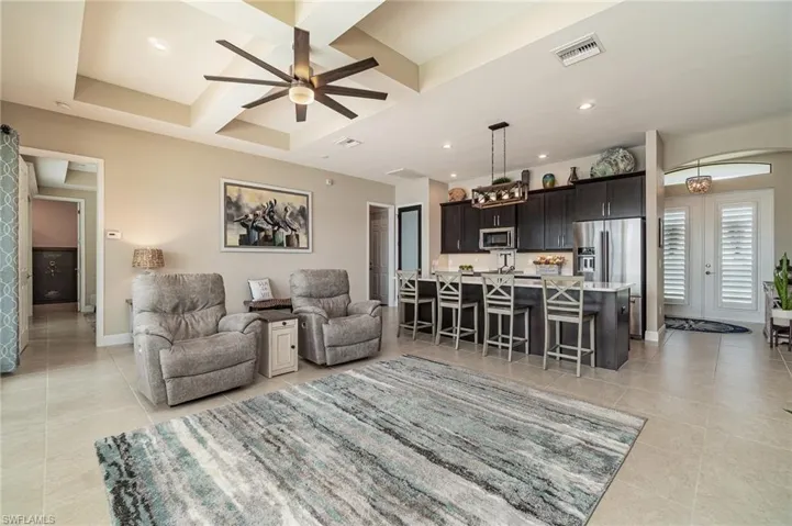 Living room with ceiling fan, beam ceiling, light tile patterned floors, and coffered ceiling