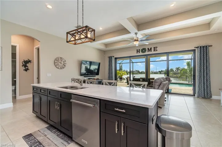 Kitchen featuring coffered ceiling, a wealth of natural light, sink, and a center island with sink
