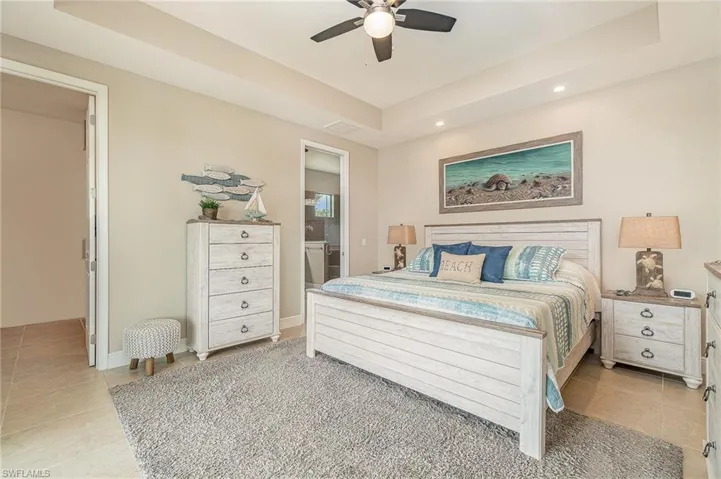 Bedroom featuring ensuite bathroom, ceiling fan, and light tile patterned flooring
