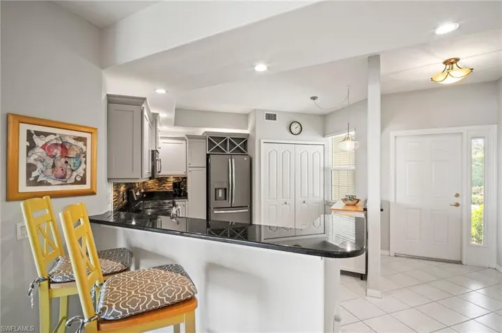 Kitchen featuring stainless steel appliances, a peninsula, gray cabinetry, light tile patterned floors, and tasteful backsplash