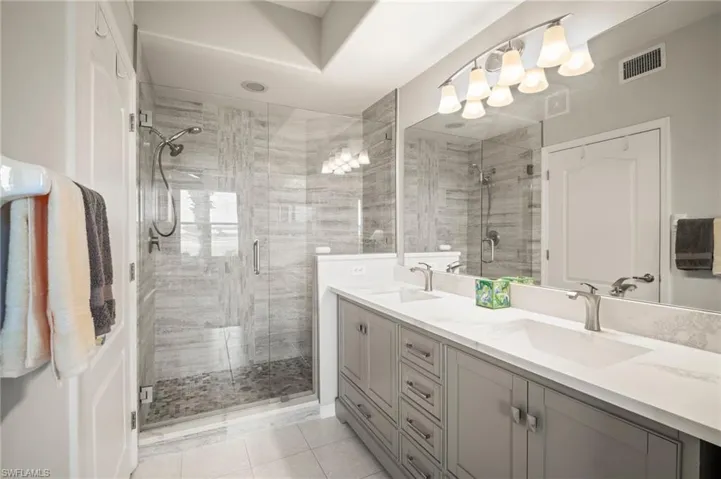 Bathroom featuring double vanity, a shower stall, and tile patterned flooring