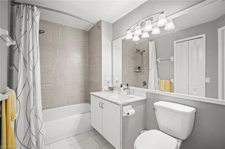 Bathroom featuring shower / bath combo with shower curtain, tile patterned flooring, vanity, and toilet