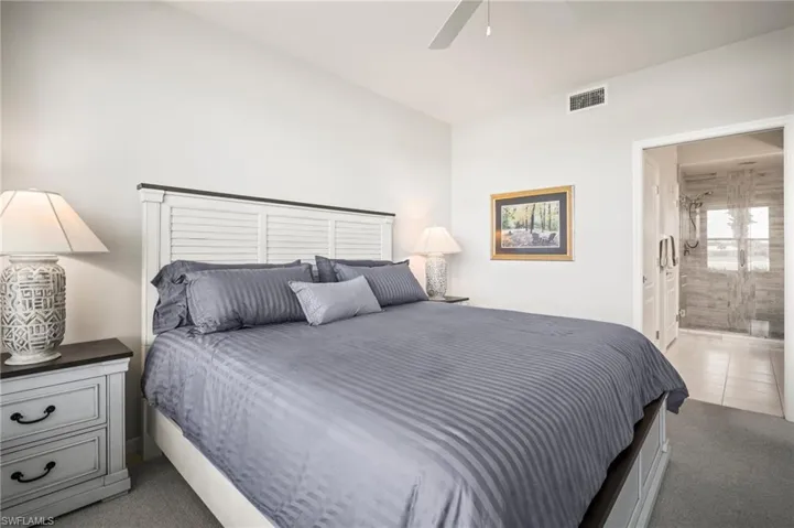 Bedroom with light colored carpet, ensuite bathroom, and ceiling fan