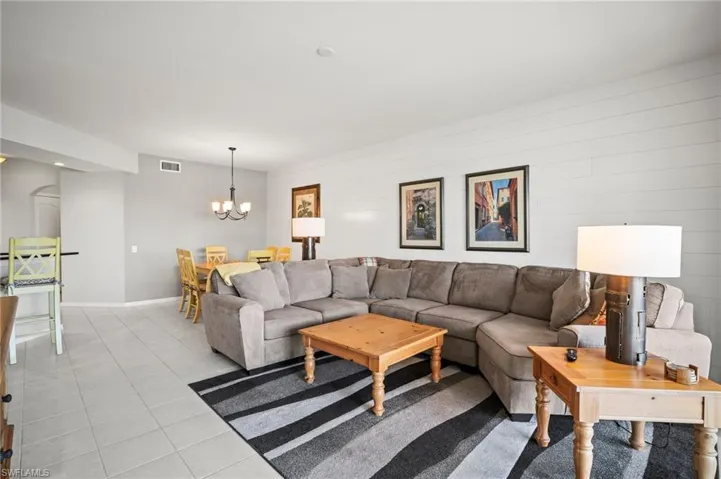 Living area with a chandelier, light tile patterned floors, and baseboards