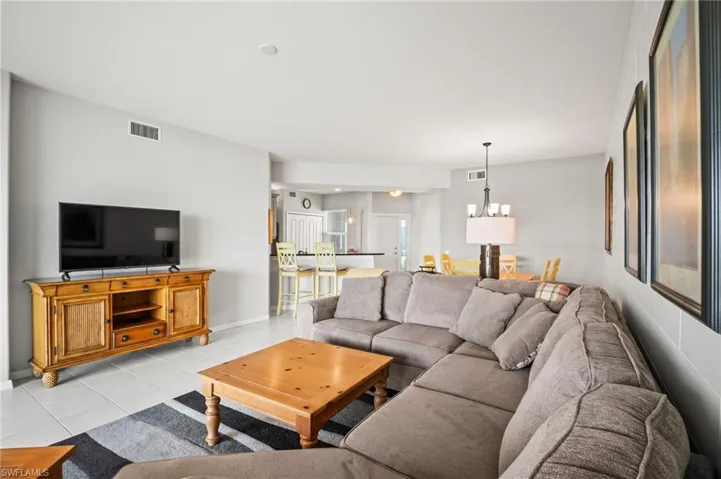 Living area with light tile patterned flooring, baseboards, and a chandelier