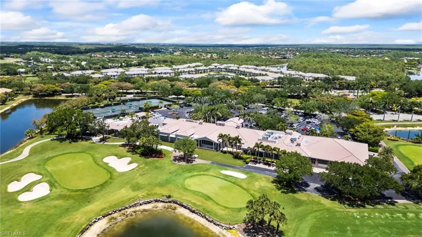 Aerial view of property and surrounding area with a large body of water, a golf course, and a tree filled landscape