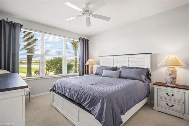 Bedroom with light carpet, baseboards, and a ceiling fan