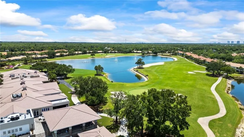 Aerial view of residential area featuring a golf club, a nearby body of water, and a tree filled landscape