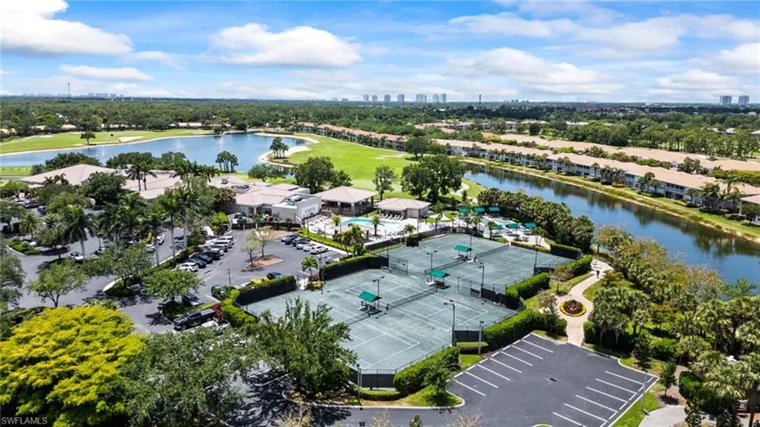 Drone / aerial view of a nearby body of water, a golf course, and a tree filled landscape