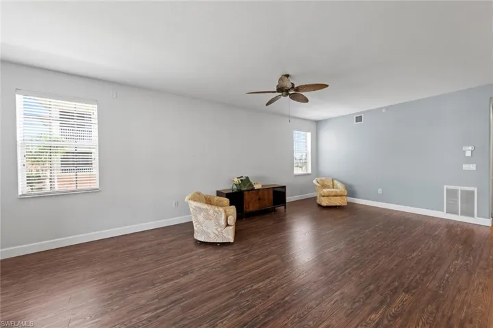 Unfurnished room featuring a ceiling fan, visible vents, and dark wood-type flooring