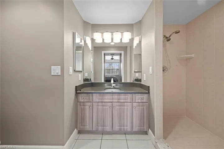 Bathroom featuring vanity, baseboards, tiled shower, and tile patterned floors