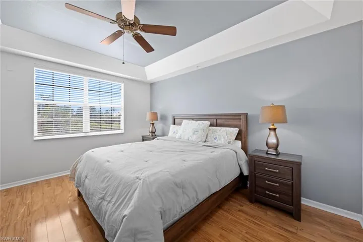 Bedroom with a raised ceiling, baseboards, a ceiling fan, and wood finished floors