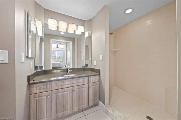 Ensuite bathroom featuring tile patterned flooring, ensuite bath, vanity, and a walk in shower