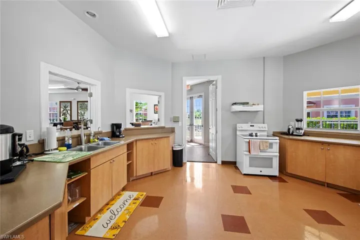 Clubhouse meetins space  with a sink, light floors, open shelves, and range with two ovens