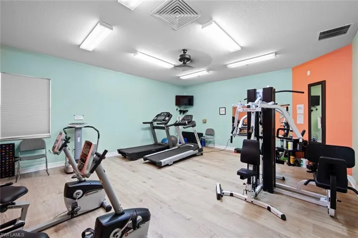 Exercise room featuring baseboards, visible vents, and wood finished floors