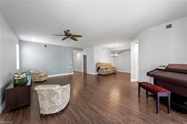 Living area featuring visible vents, dark wood-style floors, and ceiling fan with notable chandelier