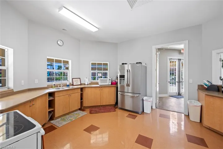 Clubhouse with a wealth of natural light, white appliances, light floors, and a sink
