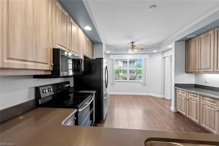 Kitchen featuring wood finished floors, recessed lighting, a ceiling fan, double oven range, and dark countertops