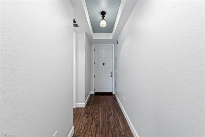 Hallway featuring  wood finished floors, baseboards, and a raised ceiling