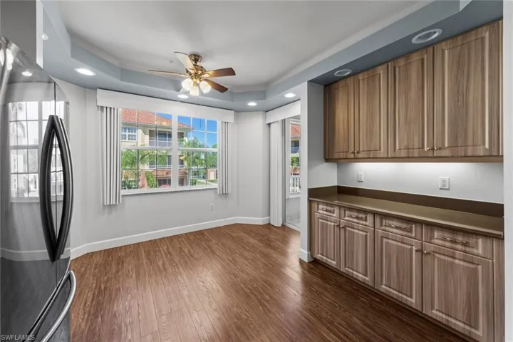 Kitchen with freestanding refrigerator, a ceiling fan, baseboards, dark wood finished floors, and dark countertops