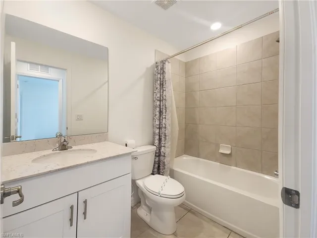 Full bathroom with shower / bathtub combination with curtain, tile patterned flooring, toilet, and vanity