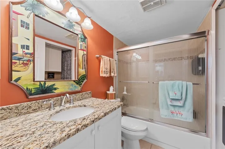 Bathroom featuring shower / bath combination with glass door, vanity, and light tile patterned floors