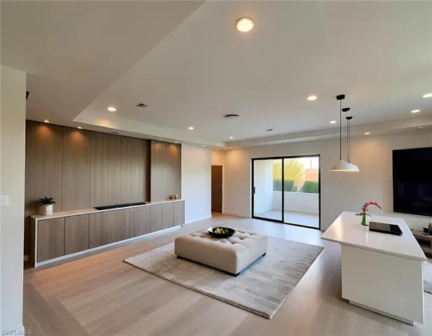 Living room with light wood-style floors, recessed lighting, and a raised ceiling