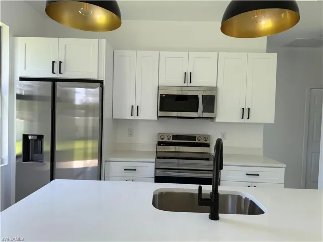 Kitchen with stainless steel appliances, light countertops, and white cabinets