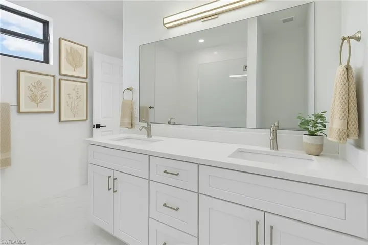 Bathroom with double vanity and marble finish flooring