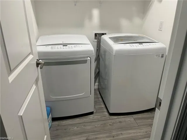Laundry room with light wood-style flooring and washing machine and clothes dryer