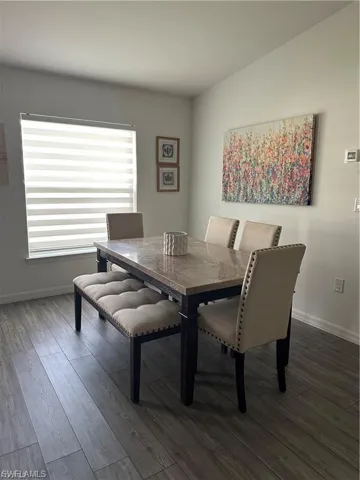 Dining area with dark wood-type flooring and baseboards