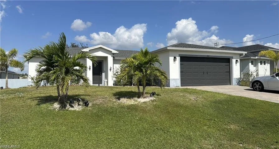 Ranch-style home with a front lawn, stucco siding, driveway, and an attached garage