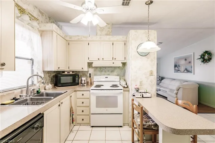 Kitchen featuring light tile patterned flooring, sink, ceiling fan, pendant lighting, and black appliances