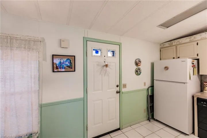 Kitchen with a textured ceiling, white refrigerator, dishwasher, and light tile patterned floors