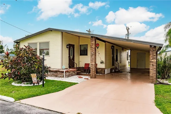 Manufactured / mobile home featuring a front yard and a carport