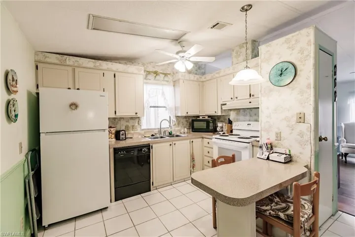 Kitchen featuring ceiling fan, decorative backsplash, sink, kitchen peninsula, and black appliances