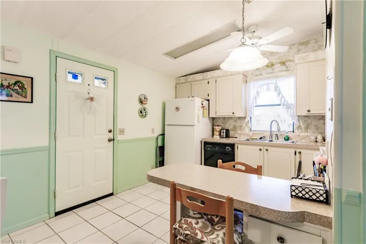 Kitchen with backsplash, white cabinetry, dishwasher, white fridge, and sink