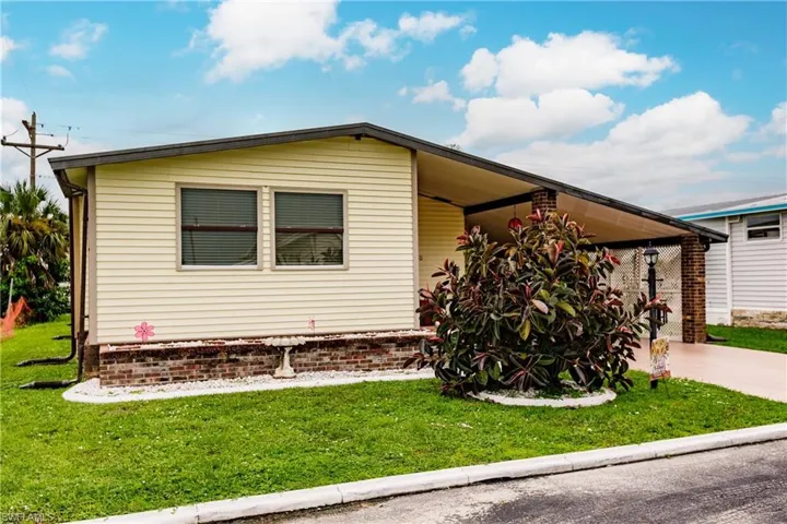 View of front facade featuring a carport and a front yard