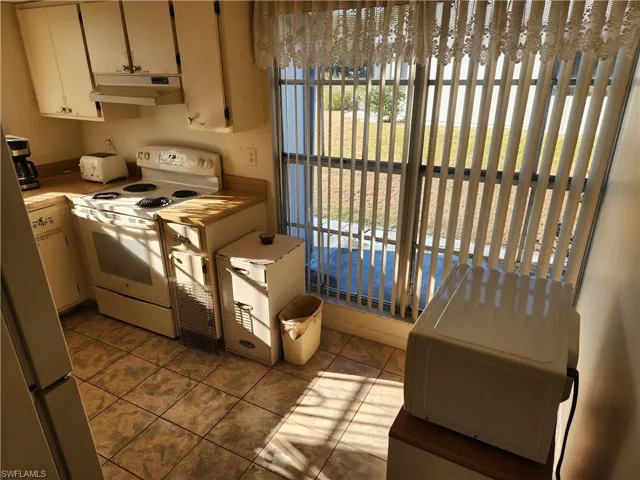 Kitchen with white appliances and dark tile patterned flooring